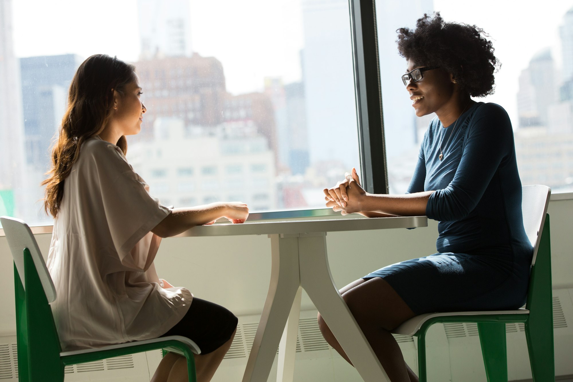 Twee vrouwen die rustig met elkaar in gesprek zijn aan een tafel
